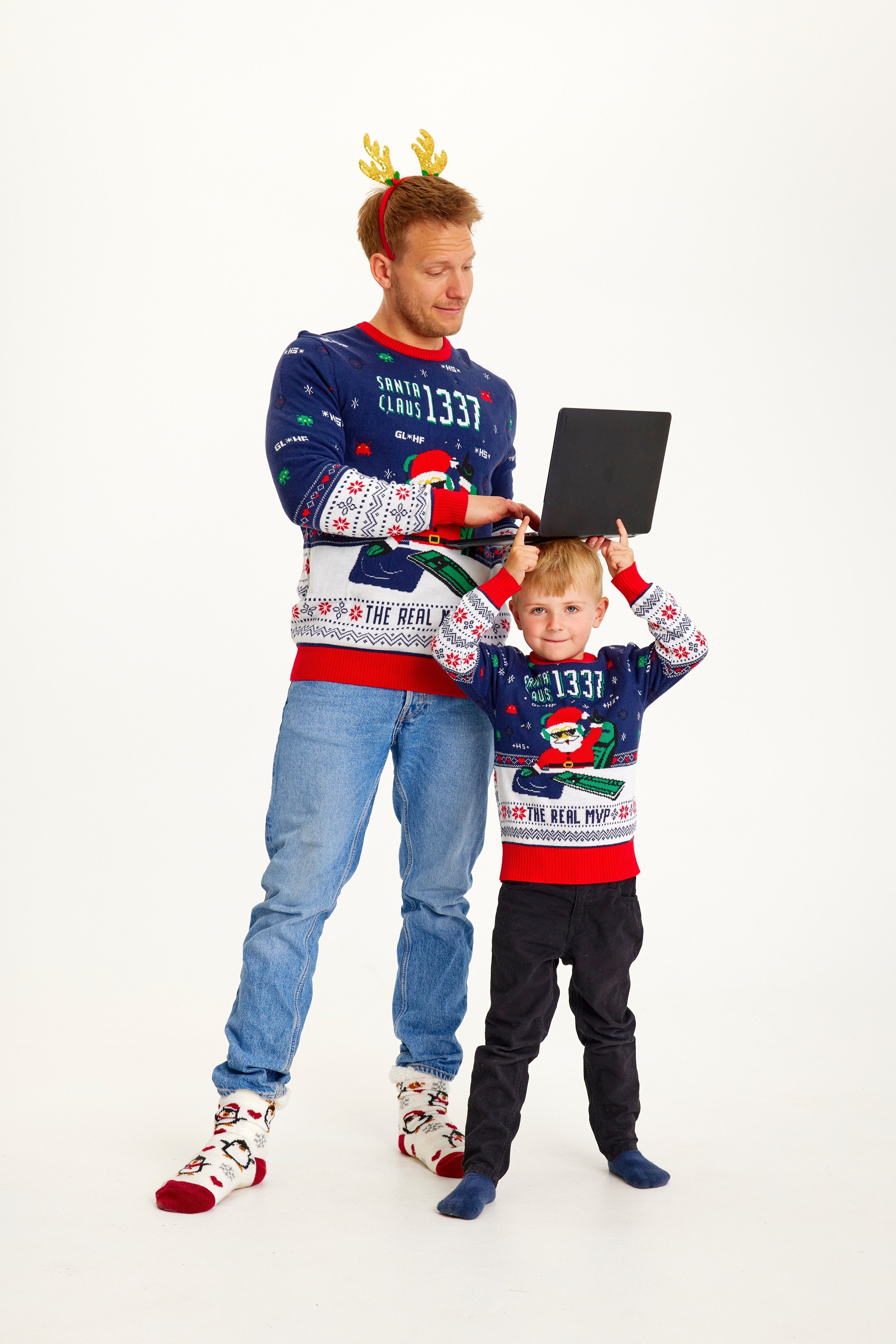 Een man en een kind die een blauwe, rode en witte kersttrui dragen met de kerstman erop.